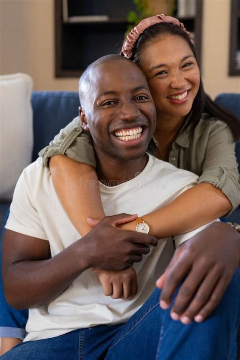 Smiling Multiracial Couple Embracing on Couch, Enjoying Quality Time at ...