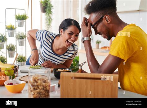 Multiethnic couple laughing, breakfasting together in the kitchen Stock ...
