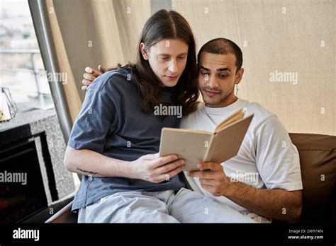 A young gay couple enjoys a quiet moment together in their modern home ...