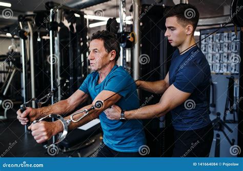 A Senior Man with a Young Trainer Doing Strength Workout Exercise in ...