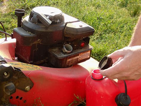 Lawn Mowing A Man Fills Up A Lawn Mower With Gasoline Refilling The Fuel Tank In A Petrol Lawn ...