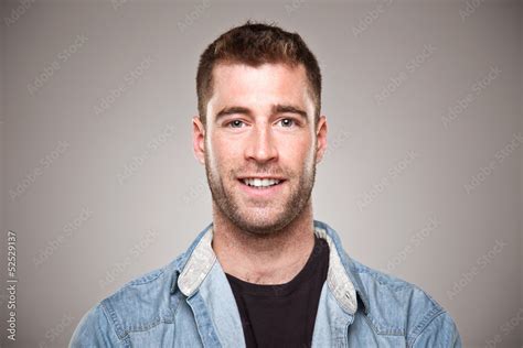 Portrait of a normal young man smiling over grey background. Stock ...