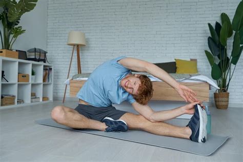 Premium Photo | Confident young man in sports clothing doing stretching exercise at home