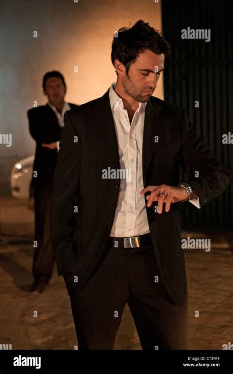 Man in suit checking his watch at night Stock Photo - Alamy