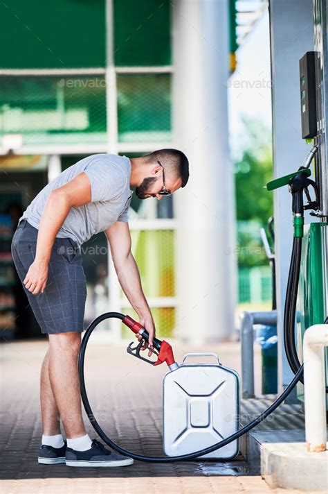 Side view of young driver filling canister with gasoline. Stock Photo by anatoliy_gleb