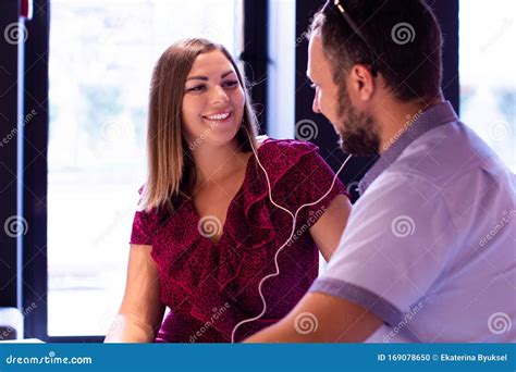 Young Adult Couple Listening To Music Together, Laughing and Looking at ...