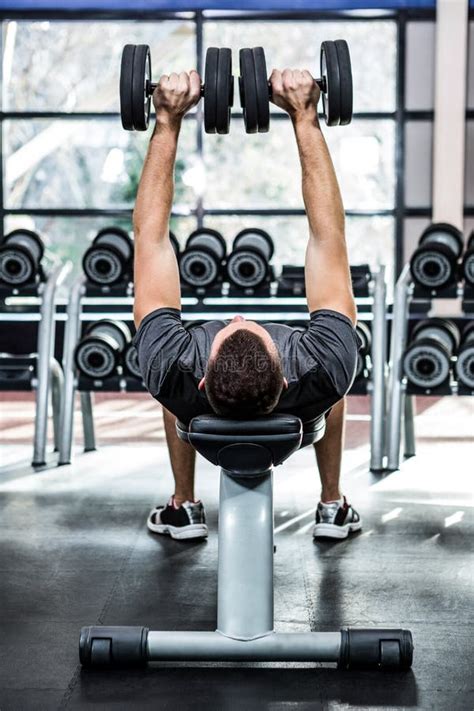 Man Lifting Dumbbells While Lying On Bench At Gym Stock Photo - Image ...