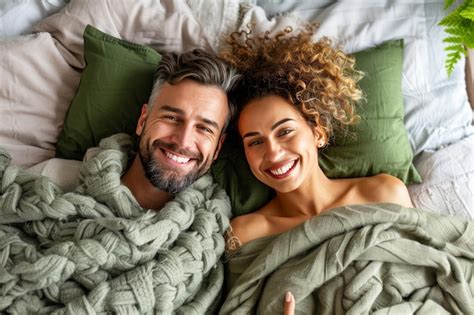 Happy young couple in bed enjoying quality time together top view of beautiful and joyful couple ...