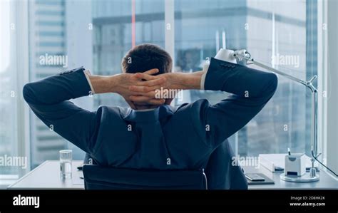 Back View of Confident Businessman Sitting at His Desk and Stretches ...