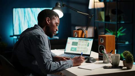 Black man organizing his schedule with a planner and putting a reminder ...