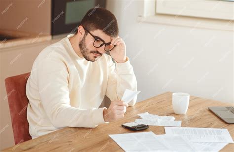 Premium Photo | Focused man reviewing finances at table in home office ...