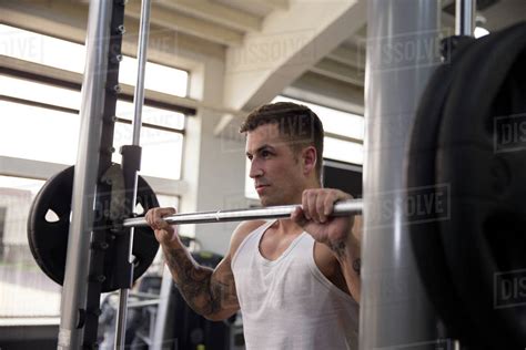 Young man lifting weights in gym - Stock Photo - Dissolve