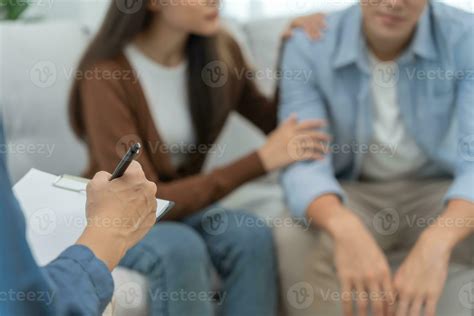 Couple hold hand support each while discussing family issues with psychiatrist. Husband ...