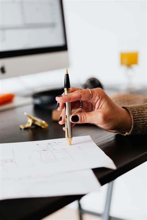 Focused Asian employee writing in diary at office desk · Free Stock Photo