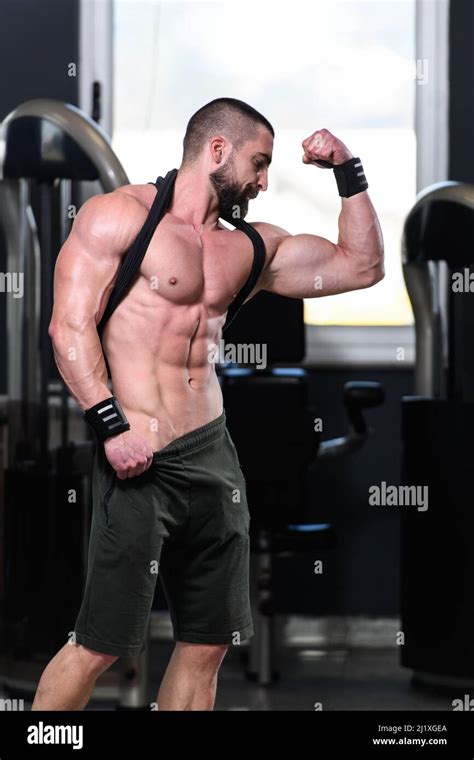 Handsome Young Man Standing Strong In The Gym And Flexing Muscles ...